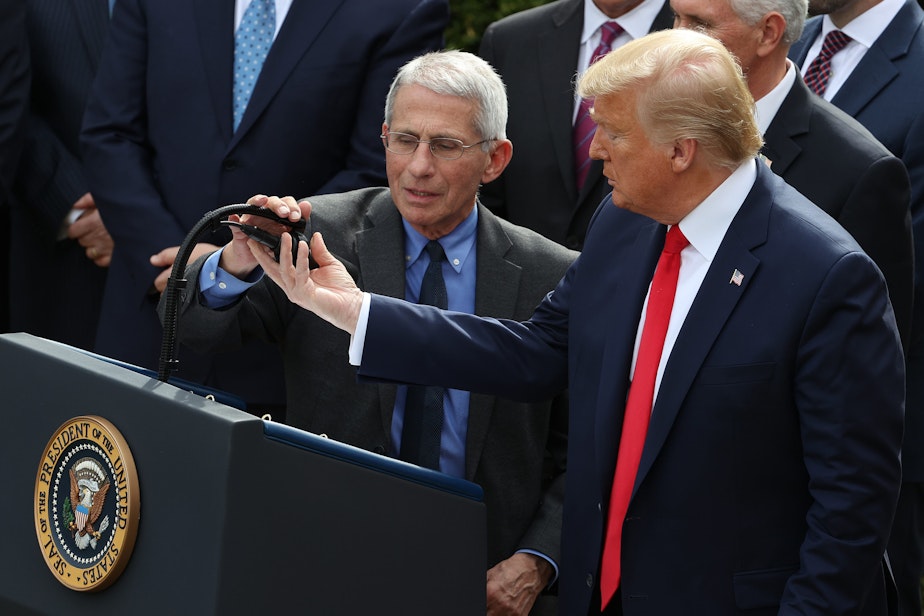 caption: U.S. President Donald Trump adjusts the microphone for National Institute Of Allergy And Infectious Diseases Director Anthony Fauci during a news conference where Trump announced a national emergency in response to the ongoing global coronavirus pandemic in the Rose Garden at the White House March 13, 2020 in Washington, DC.  (Chip Somodevilla/Getty Images)