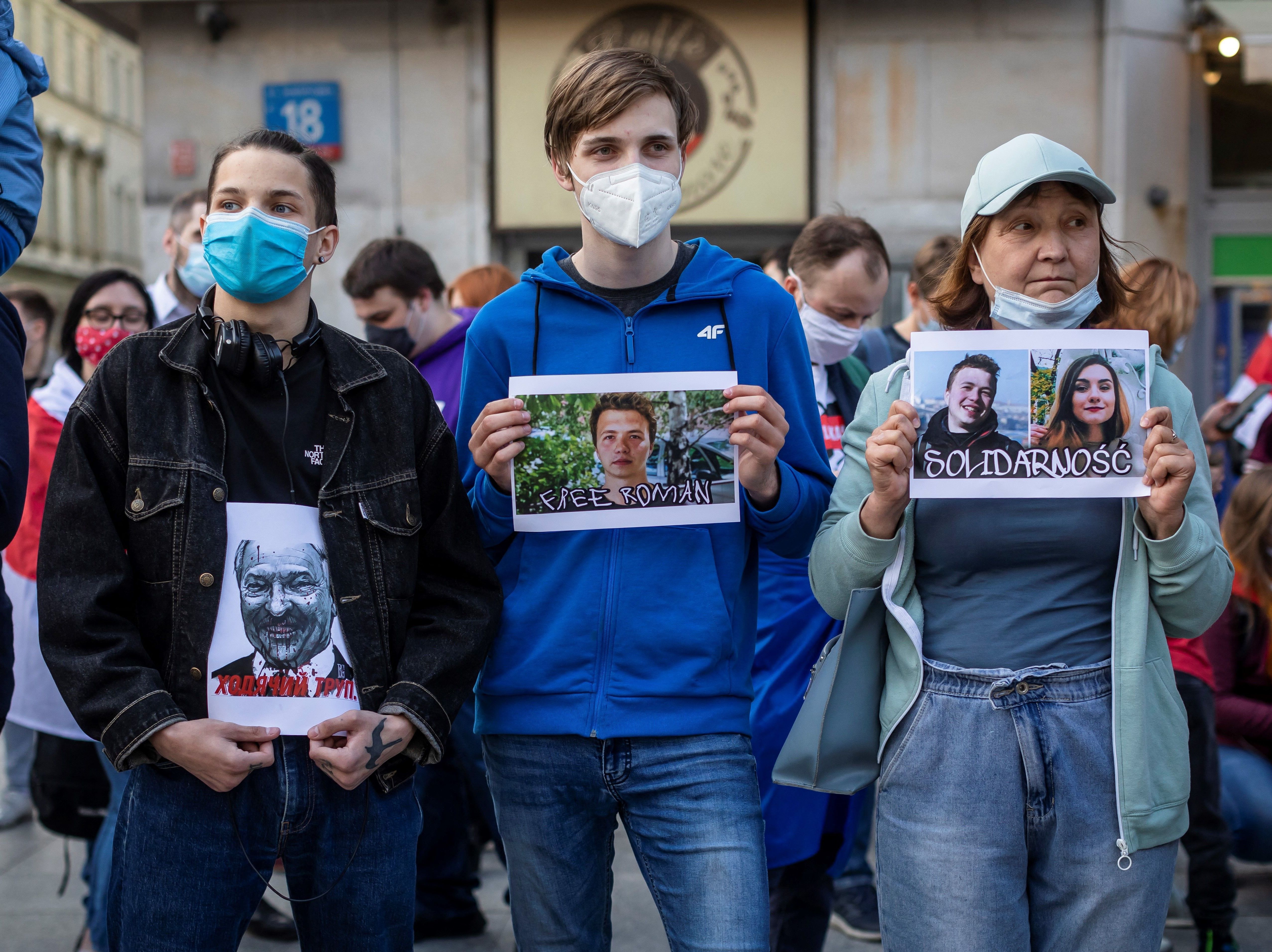 caption: Protesters hold images of Belarus strongman Alexander Lukashenko, Belarus opposition activist Roman Protasevich and Protasevich's partner Sofia Sapega during a demonstration of Belarusians living in Poland and Poles supporting them in front of European Commission office in Warsaw on Monday.