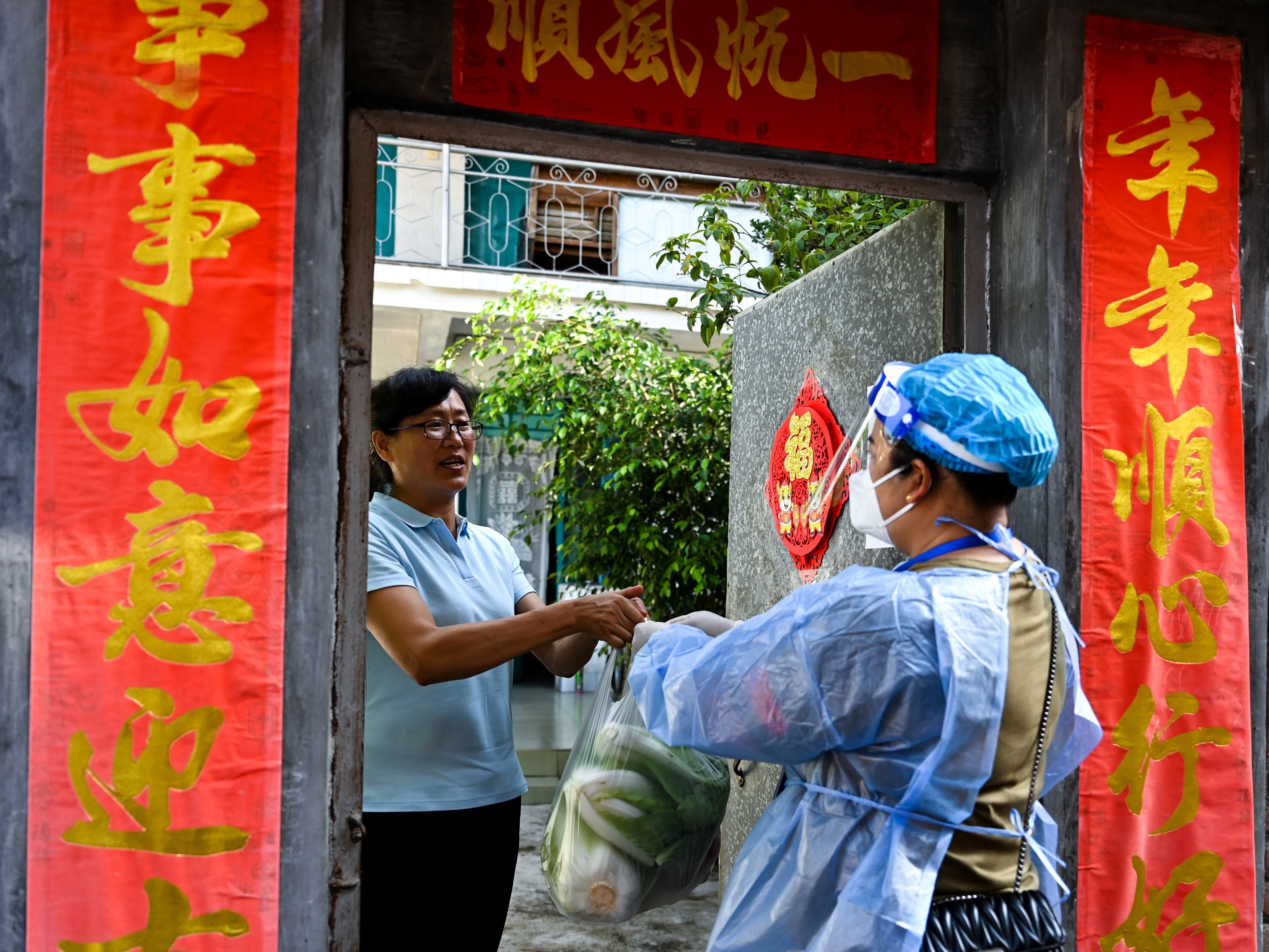 caption: A community worker delivers daily necessities to a household during quarantine conditions in the southwestern Chinese city of Ruili. Residents have taken to social media to complain about what they describe as harsh lockdown measures brought on by China's zero COVID policy.