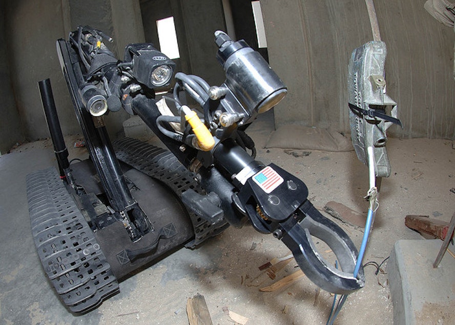caption: Technicians from a Explosive Ordnance Disposal unit use a robot to disarm a mine during a training mission.
