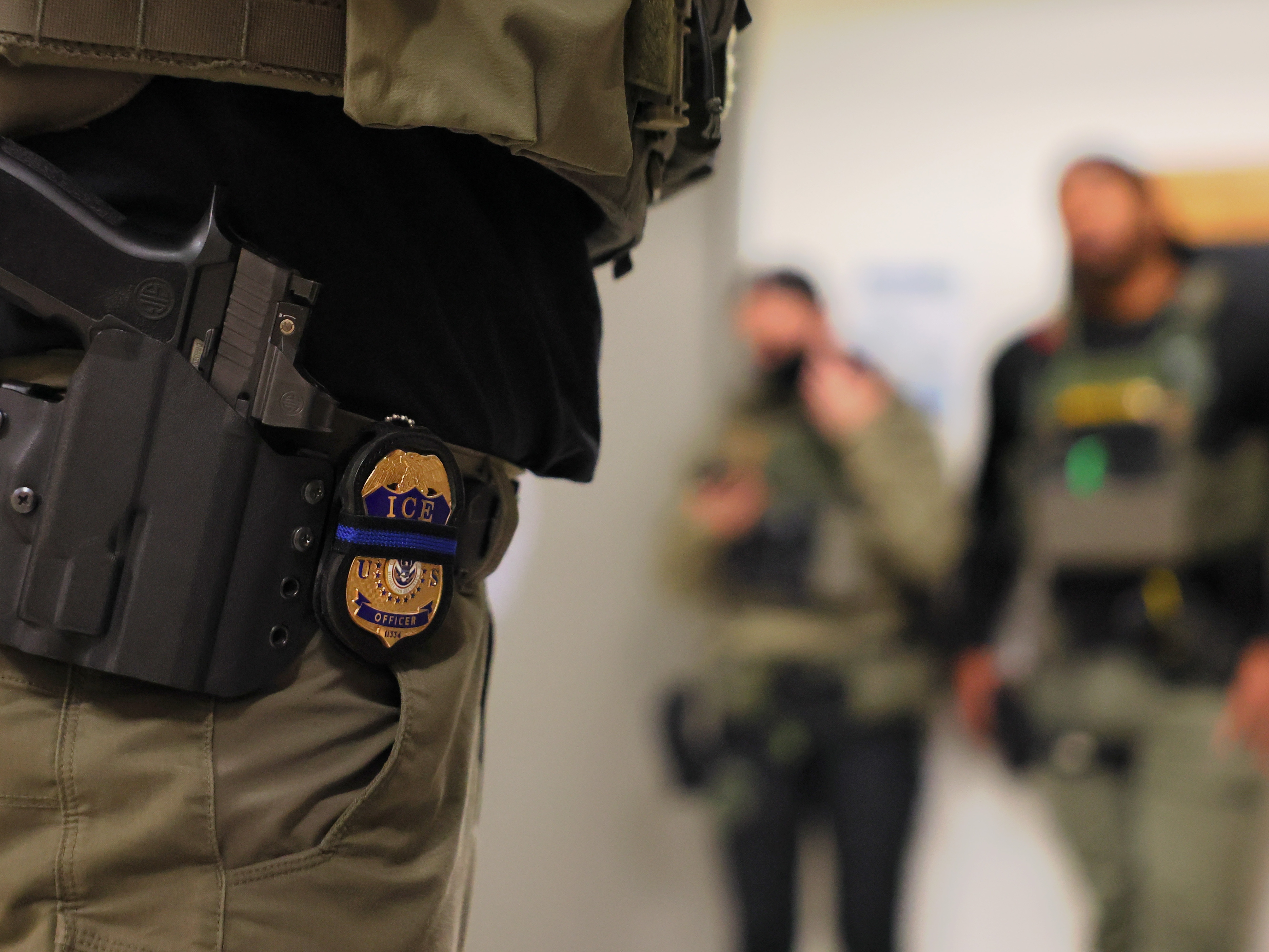 caption: An ICE officer's badge is seen as federal agents patrol the halls of immigration court at the Jacob K. Javitz Federal Building on June 10 in New York City.