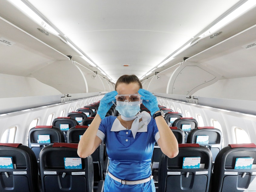 caption: A flight attendant adjusts protective glasses.