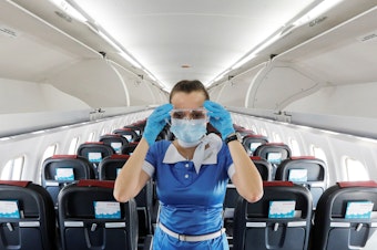 caption: A flight attendant adjusts protective glasses.