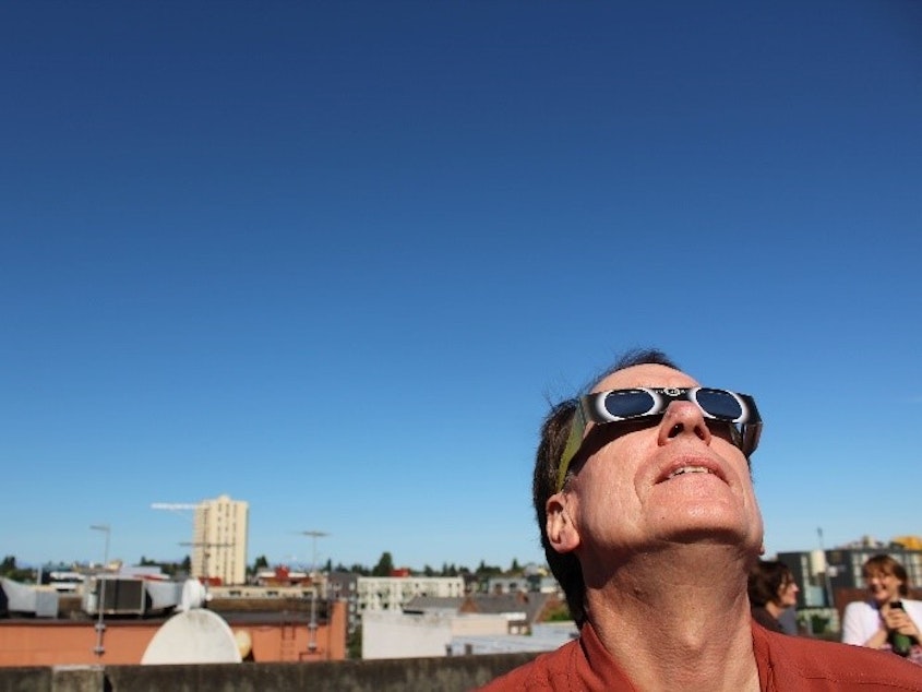 caption: Ross Reynolds catches a solar eclipse from the KUOW rooftops. 