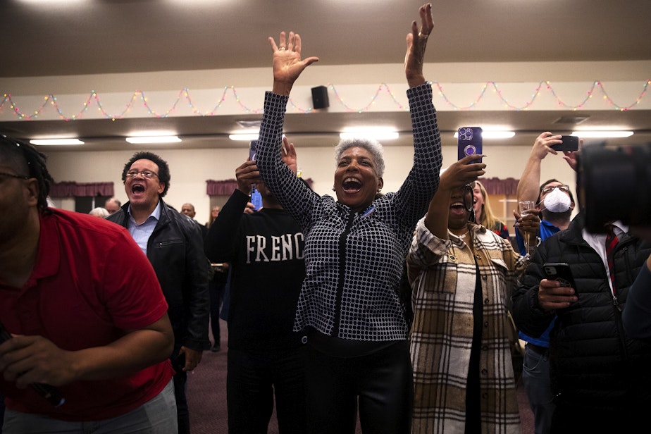caption: Jacqueline Hollingsworth Roberts, center, celebrates as election results displayed on a screen show her niece, Seattle City Council candidate in the 3rd District, Joy Hollingsworth, in the lead during an election night party at the First AME Church on Tuesday, Nov. 7, 2023, in Seattle.