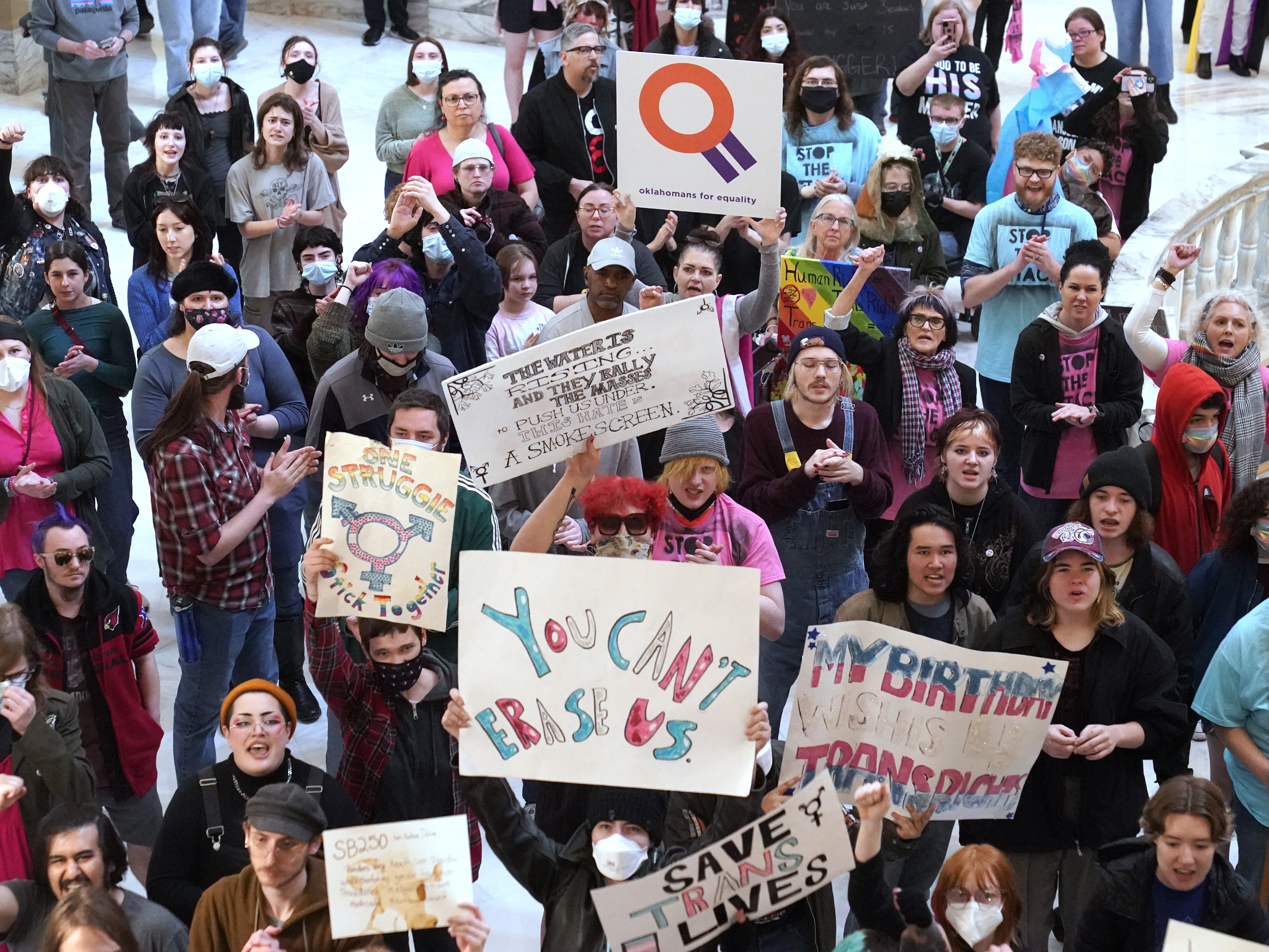 caption: Trans-rights activists protest outside the House chamber at the Oklahoma state capitol before the State of the State address, Feb. 6, 2023, in Oklahoma City. Oklahoma and 25 other states have anti-trans laws on the books.