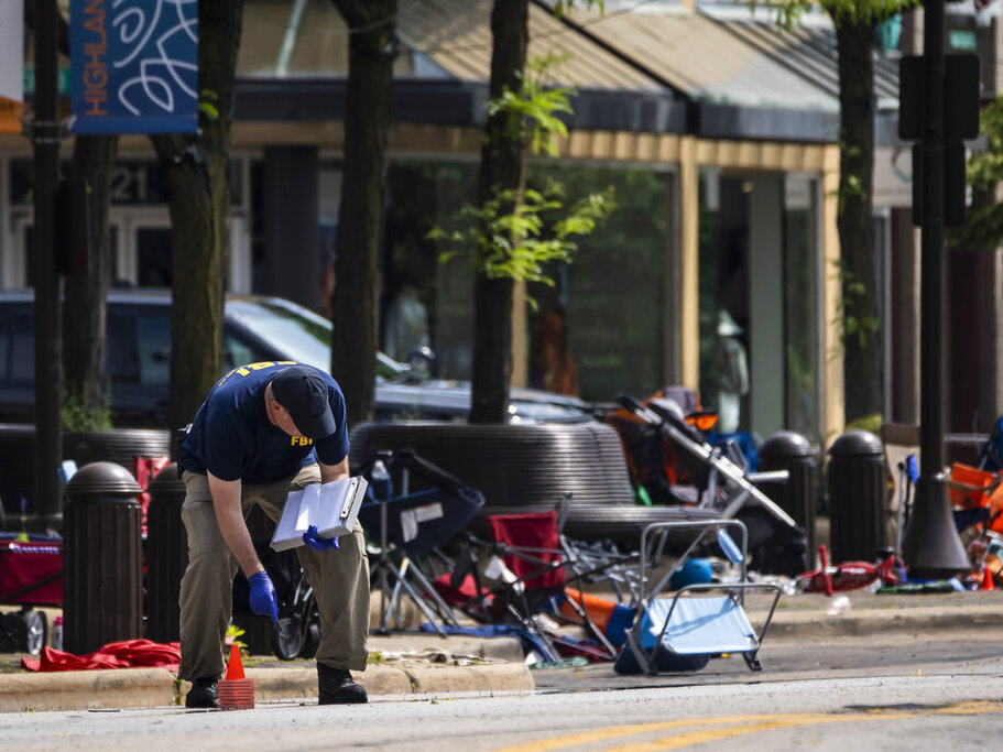 caption: Members of the FBI's Evidence Response Team Unit investigate Tuesday in downtown Highland Park, Ill., the day after a deadly mass shooting. Police say the gunman who attacked an Independence Day parade in suburban Chicago fired more than 70 rounds with an AR-15-style gun.
