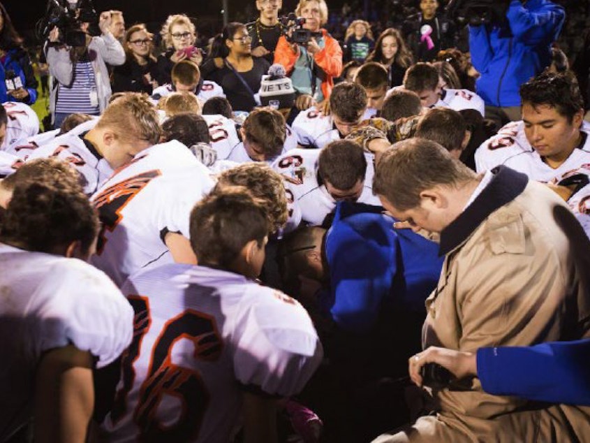 caption: The parties included this image, of Coach Kennedy praying with a crowd after the homecoming game, in their joint appendix submitted to the Supreme Court