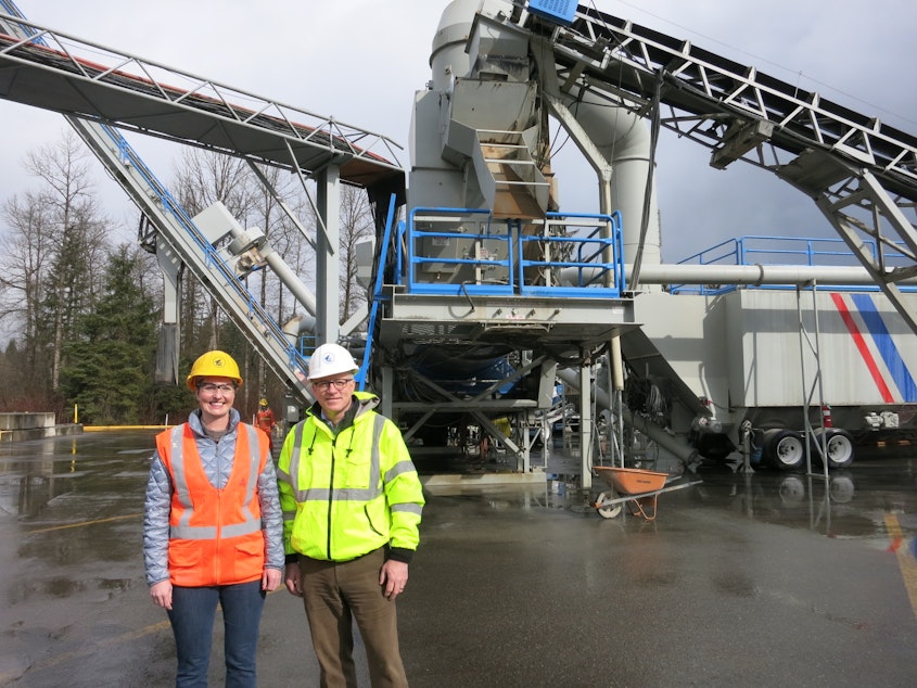 caption: Lakeside Industries environmental director, Karen Deal, and president, Mike Lee, pose in front of the company's asphalt plant in Covington. The company plans to relocate this equipment to a new site across from the Cedar River. 