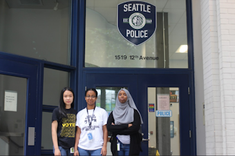caption: RadioActive's Hong Ta, Essey Paulos and Marian Mohamed stand outside the Seattle Police department in Capitol Hill. 