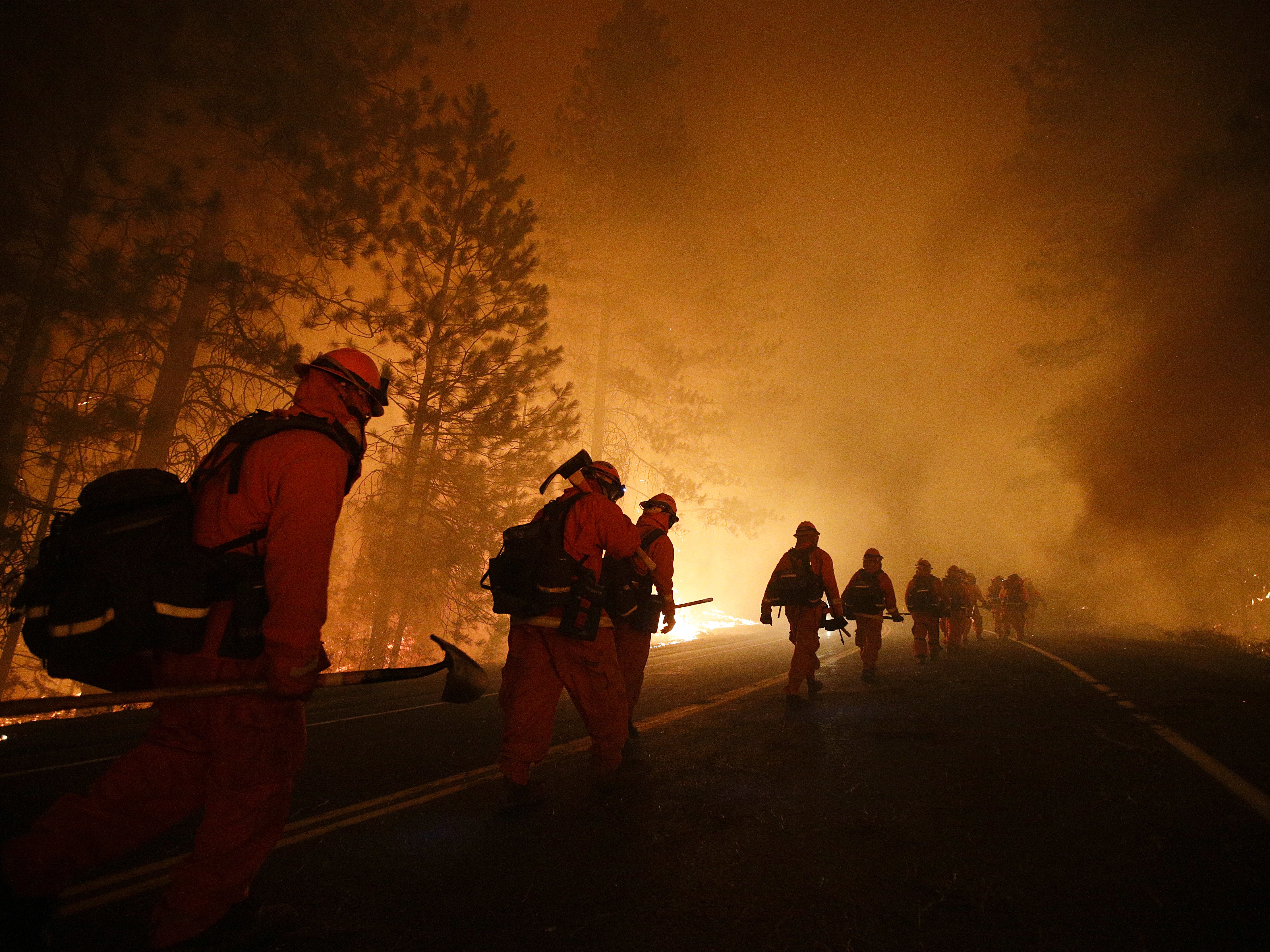 caption: Inmate firefighters walk along Highway 120 during the Rim Fire near Yosemite National Park, Calif. in 2013. California currently has about 400 inmate firefighters battling the LA county wildfires.