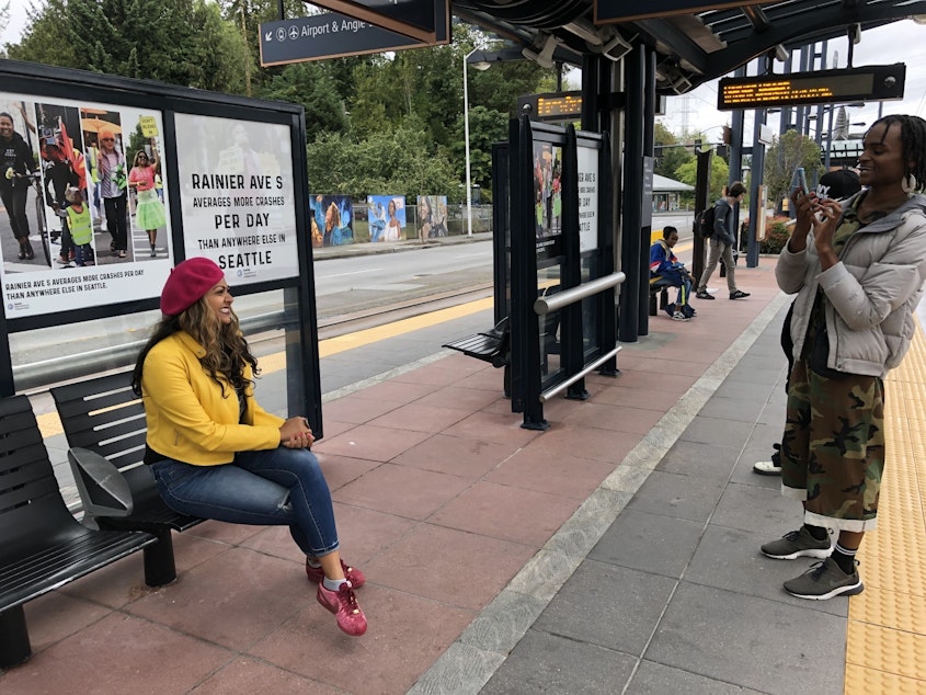 caption: Randy Ford takes a photo of Priya Frank in front of a "Don't Blend In" ad she's featured on.