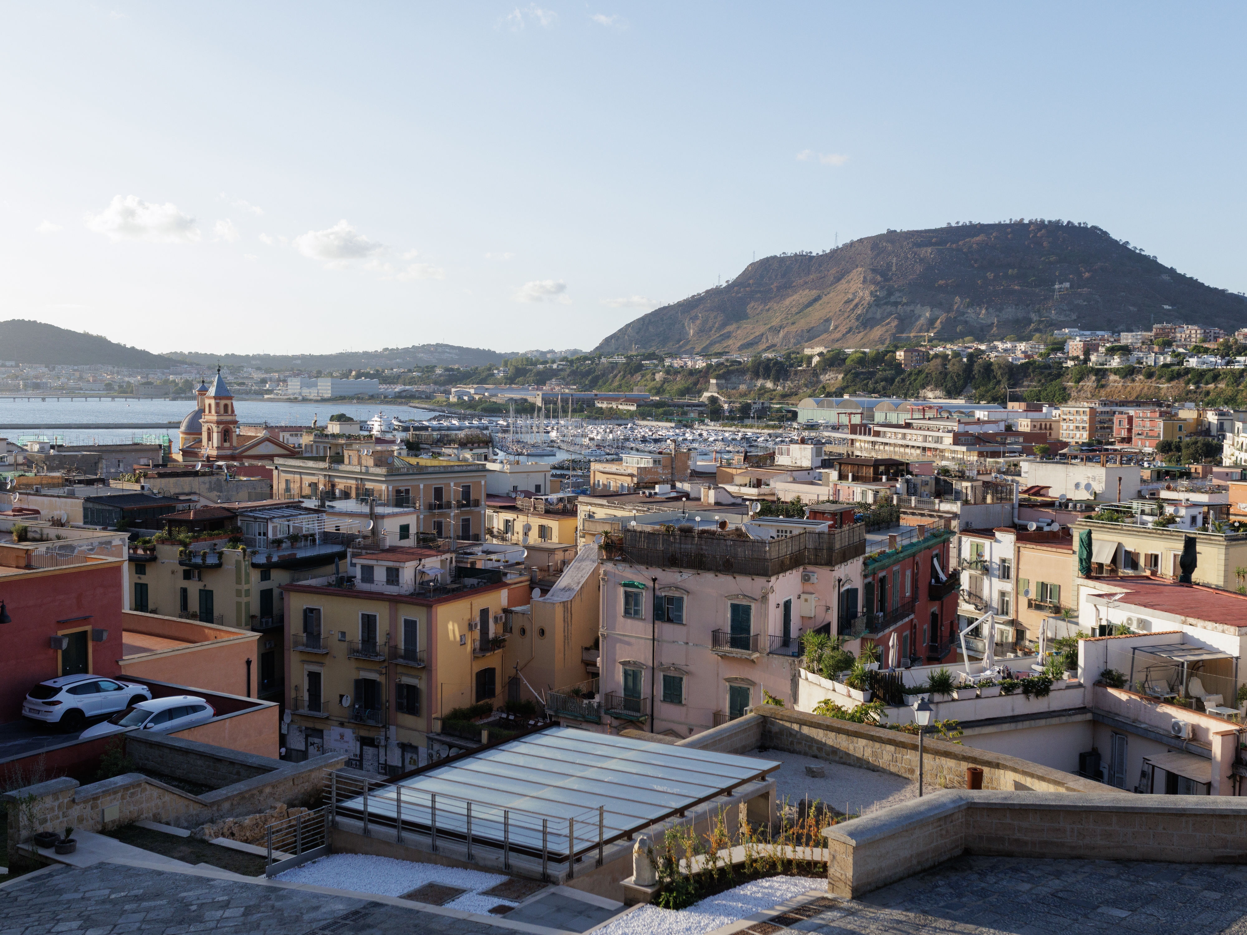 caption: Pozzuoli unfolds as seen from the Rione Terra. In the background rises the Monte Nuovo, the youngest volcanic feature of the Campi Flegrei formed by the 1538 eruption.