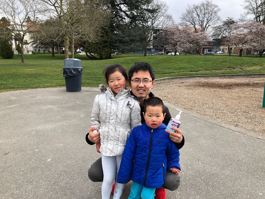caption: Chao Duan keeps hand sanitizer close while his young kids explore Greenlake Park. 