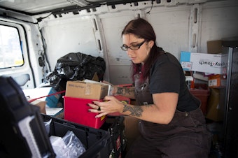 caption: Lisa Al-Hakim, Director of Operations at the People's Harm Reduction Alliance, moves a box of syringes before doing outreach along Aurora Avenue on Monday, May 6, 2019, in Seattle.