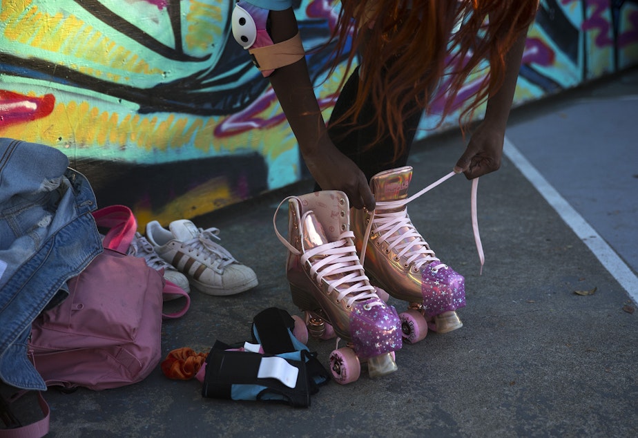 caption: Chaka Cumberbatch-Tinsley ties her skates on Monday, September 28, 2020, at the Judkins Park sports courts in Seattle.