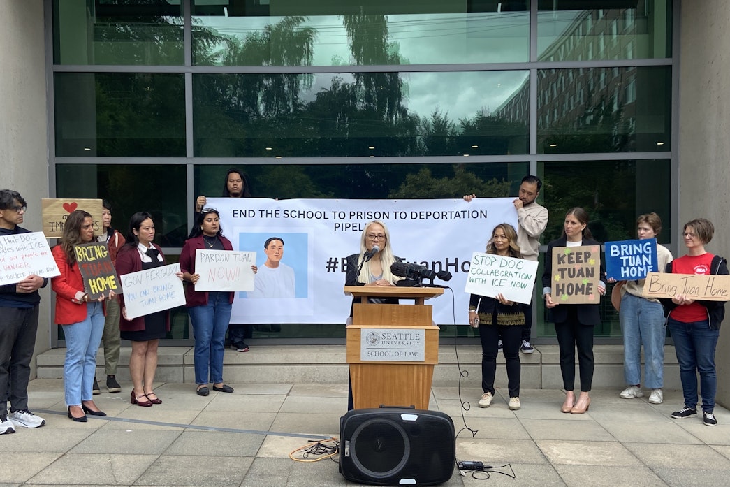caption: Ngoc Phan (center) speaks at a press conference outside of Seattle University's Sullivan Hall on June 27, 2025.