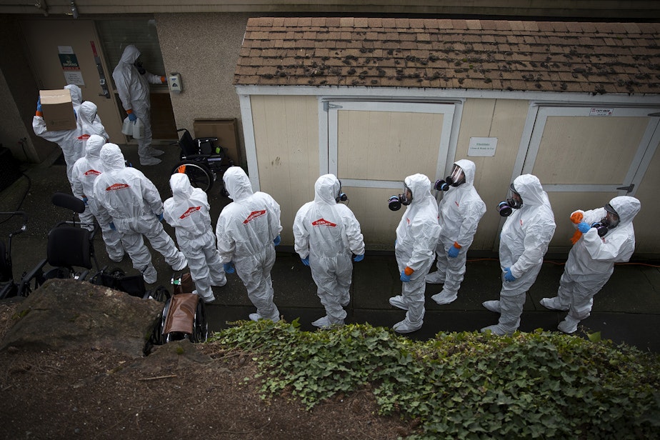 caption: Members of a Servpro cleaning crew line up before entering the Life Care Center of Kirkland, the long-term care facility at the epicenter of the coronavirus outbreak in Washington state, on Wednesday, March 11, 2020, in Kirkland. 