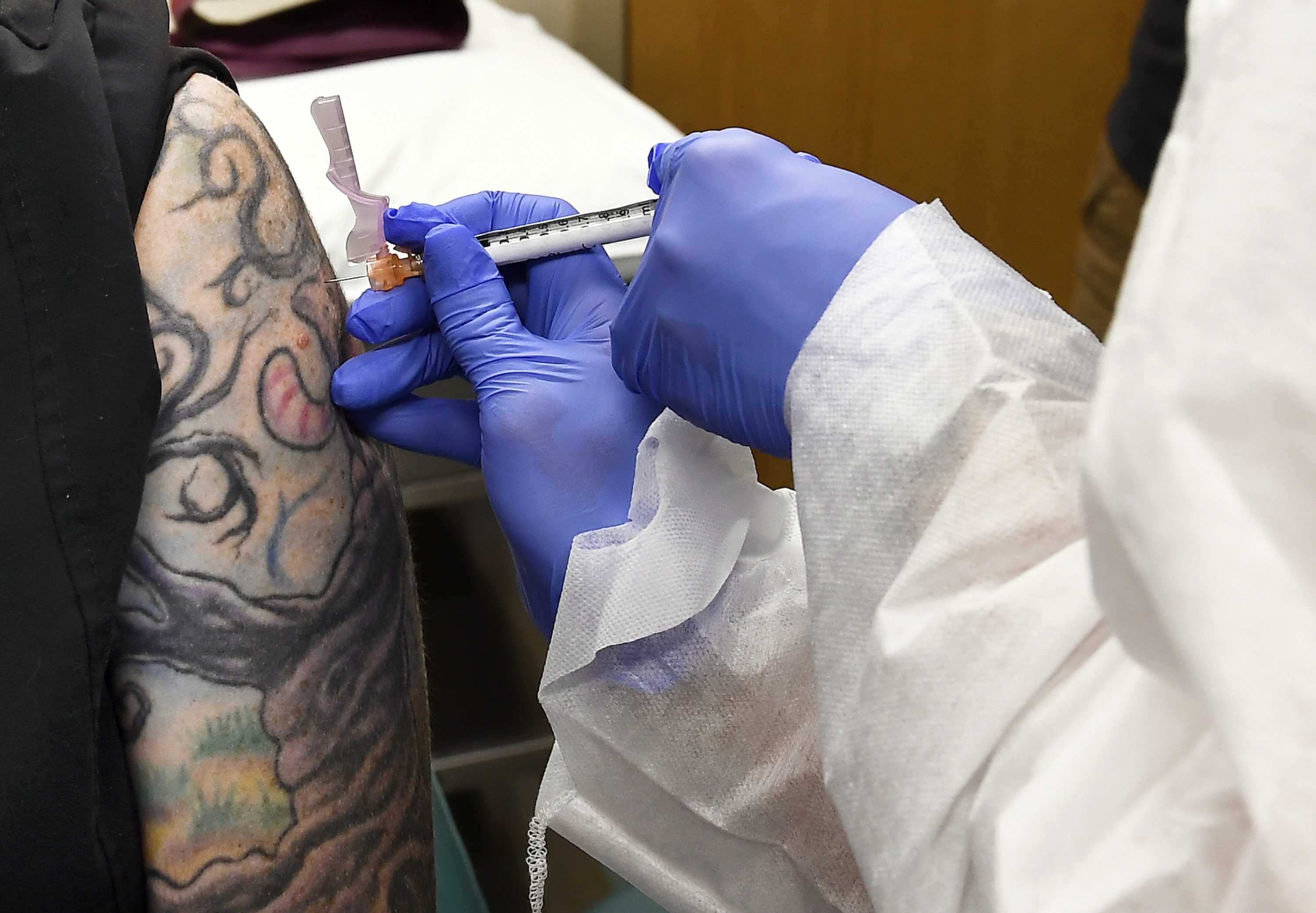 caption: Nurse Kathe Olmstead, right, gives volunteer Melissa Harting, of Harpersville, N.Y., an injection as the world's biggest study of a possible COVID-19 vaccine, developed by the National Institutes of Health and Moderna Inc., gets underway Monday, July 27, 2020, in Binghamton, N.Y. (Hans Pennink/AP Photo)