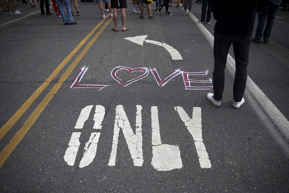 caption: 'Love' is painted on the ground at the intersection of 12th Avenue and East Pine Street, outside of the Seattle Police Department's East Precinct building, in the 'Capitol Hill Autonomous Zone', also known as CHAZ, on Wednesday, June 10, 2020, in Seattle.