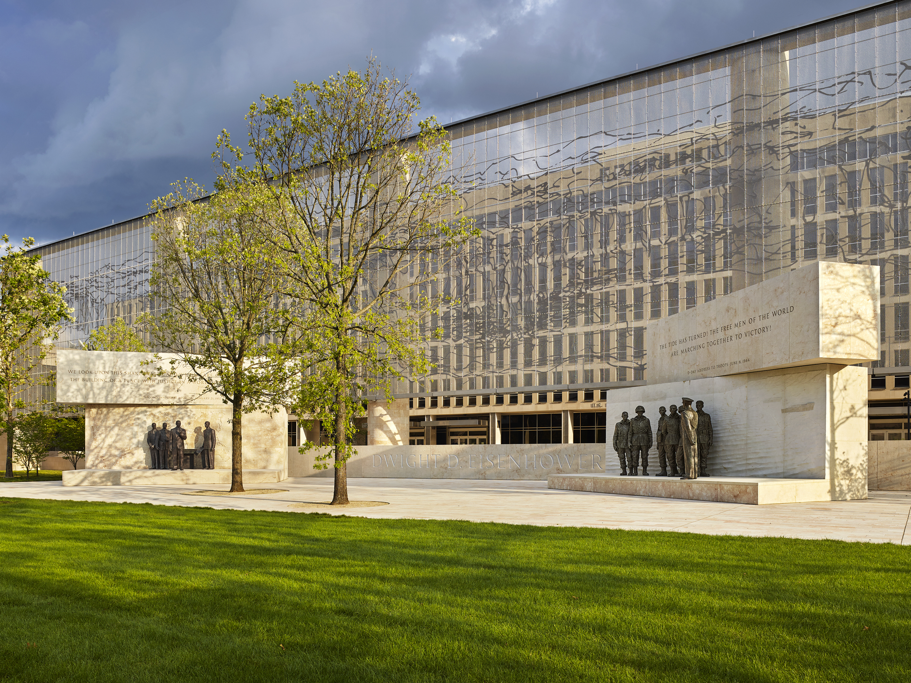 caption: The Dwight D. Eisenhower Memorial in Washington, D.C., will be dedicated on Sept. 17. A stainless steel, woven "tapestry" made by artist Tomas Osinski stands behind the statues, and depicts the cliffs at Normandy.