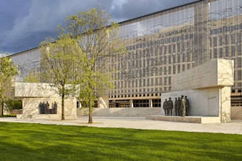 caption: The Dwight D. Eisenhower Memorial in Washington, D.C., will be dedicated on Sept. 17. A stainless steel, woven "tapestry" made by artist Tomas Osinski stands behind the statues, and depicts the cliffs at Normandy.