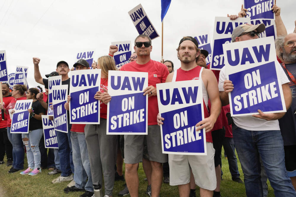 caption: Striking United Auto Workers hold picket signs near a General Motors Assembly Plant in Delta Township, Mich., Friday, Sept. 29, 2023. (Paul Sancya/AP)