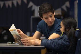 caption: Volunteer Anthony Lee reads with Elizabeth Riff on Wednesday, January 24, 2018, at Sanislo Elementary School in West Seattle. 
