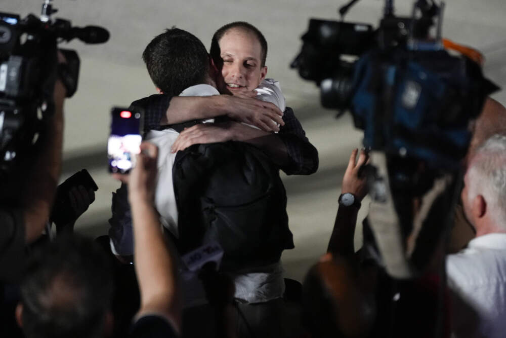 caption: Reporter Evan Gershkovich receives an embrace from a colleague following his release as part of a 24-person prisoner swap between Russia and the United States on Thursday, Aug. 1, 2024. (Manuel Balce Ceneta/AP)