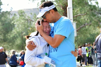 caption: A man embraces his daughter after picking her up at Central Park in Santa Clarita, Calif., after a shooting at Saugus High School on Thursday. At least two people died in the attack, according to local law enforcement.