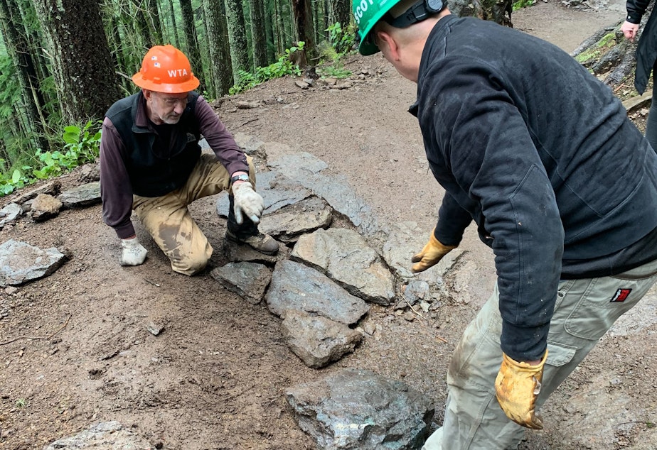 caption: Two volunteers lay stones on the Rattlesnake Ledge trail to even the grade over a drainage channel. 