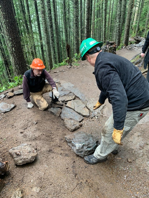 caption: Two volunteers lay stones on the Rattlesnake Ledge trail to even the grade over a drainage channel. 