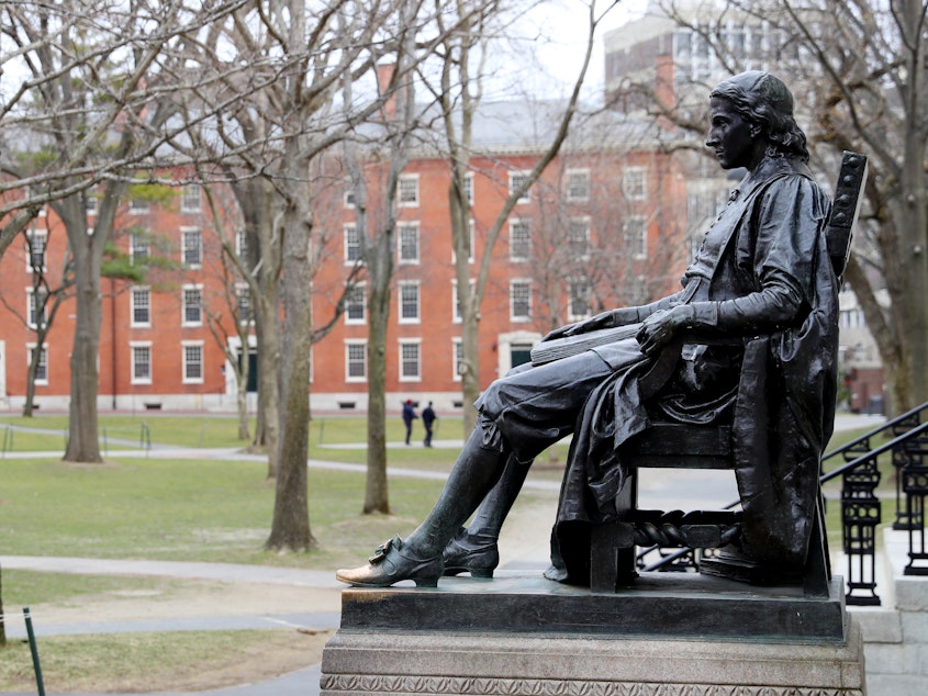 caption: A statue of John Harvard, namesake of the university, overlooks the campus earlier this year. Harvard University joined the Massachusetts Institute of Technology in suing the federal government over its policies on international students Wednesday.