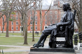 caption: A statue of John Harvard, namesake of the university, overlooks the campus earlier this year. Harvard University joined the Massachusetts Institute of Technology in suing the federal government over its policies on international students Wednesday.