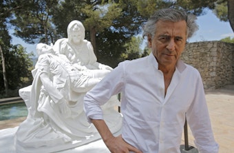caption: French philosopher Bernard-Henri Lévy poses close to sculpture "Merciful Dream" by Jan Fabre during the preparations of the "Adventures of truth" exhibition in Saint Paul de Vence, France, on June 25, 2013. (Lionel Cironneau/AP)