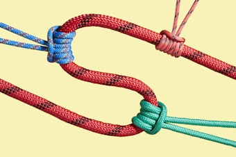 caption: Red S-shaped rope being tugged by three different knots. Each knot is a different color — blue, orange, and green. Yellow background.