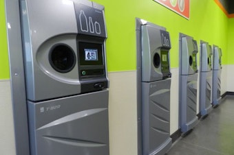 caption: A row of sparkling clean reverse vending machines greet customers at the grand opening of the Medford BottleDrop center.CREDIT: JES BURNS/EARTHFIX