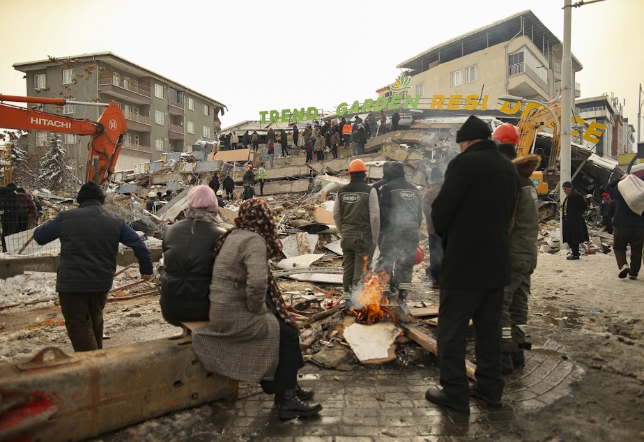caption: People and rescue workers at the scene of a collapsed building in Malatya, Turkey, Tuesday, Feb. 7, 2023. Search teams and aid are pouring into Turkey and Syria as rescuers working in freezing temperatures dig through the remains of buildings flattened by a magnitude 7.8 earthquake.