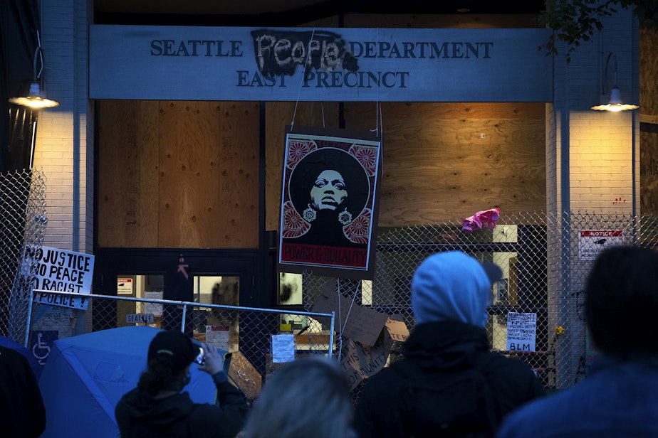 caption: A crowd gathers around the Seattle Police Department's East Precinct building at the intersection of 12th Avenue and East Pine Street on Saturday, June 13, 2020, inside the Capitol Hill Autonomous Zone, CHAZ, or Capitol Hill Occupied Protest, CHOP, in Seattle. 