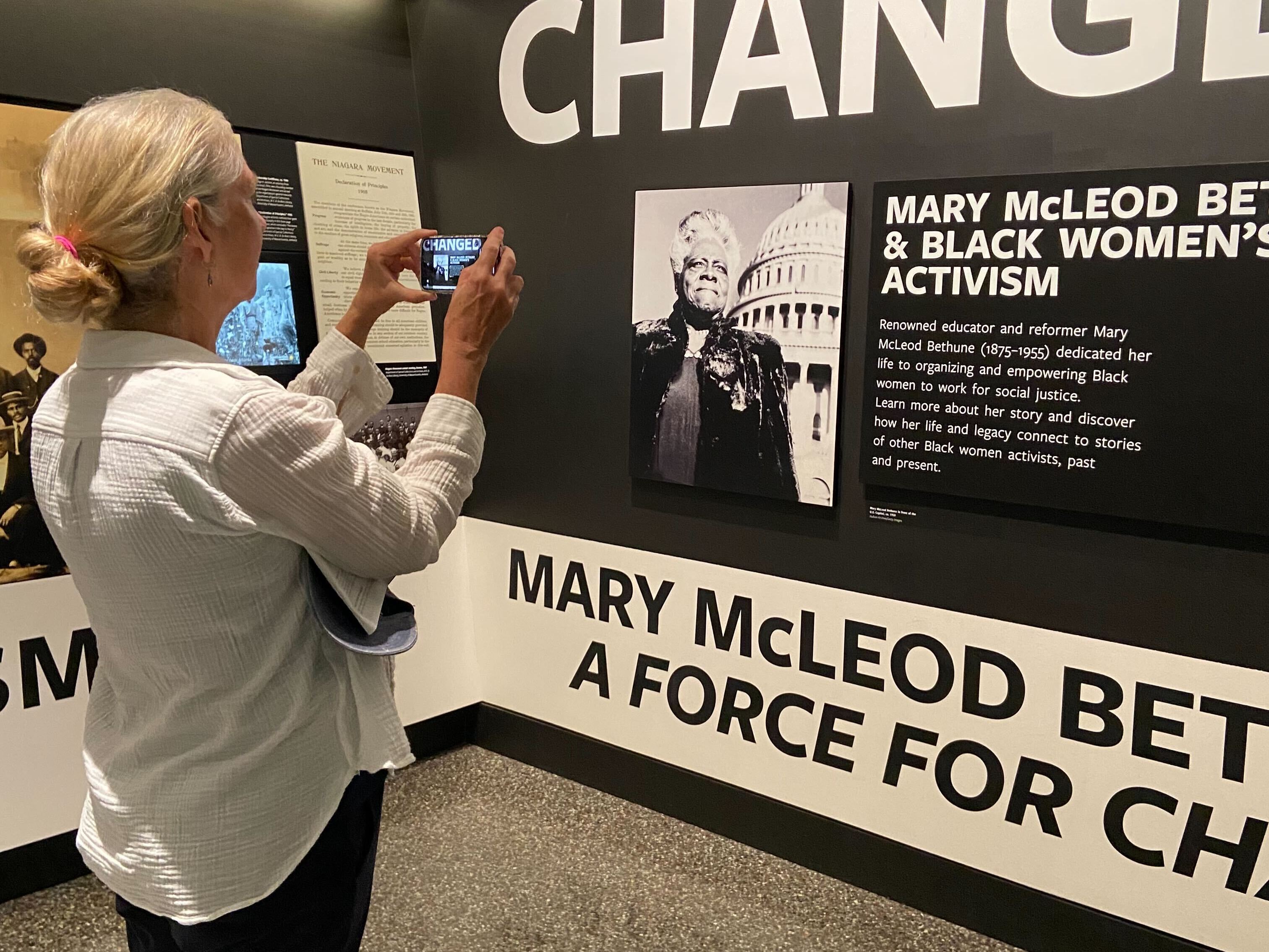 caption: Shelley Smith, a retired public health professional, is one of hundreds of volunteers taking part in an effort to document wall text, objects and images at the Smithsonian.