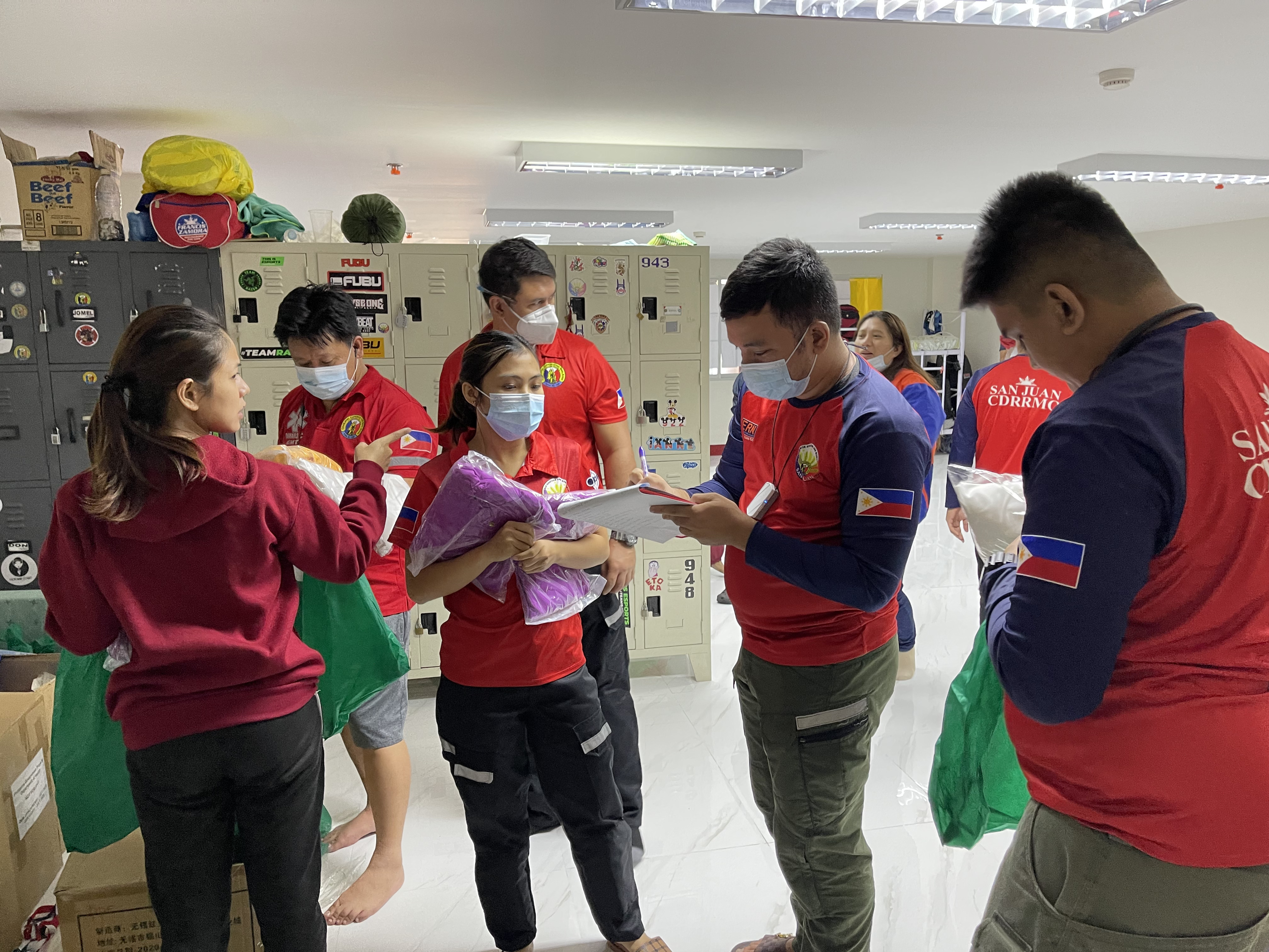 caption: Staffers distribute the required personal protective gear before they transfer a COVID-positive patient to a hospital. They'll wear a gown, gloves, mask and face shield.