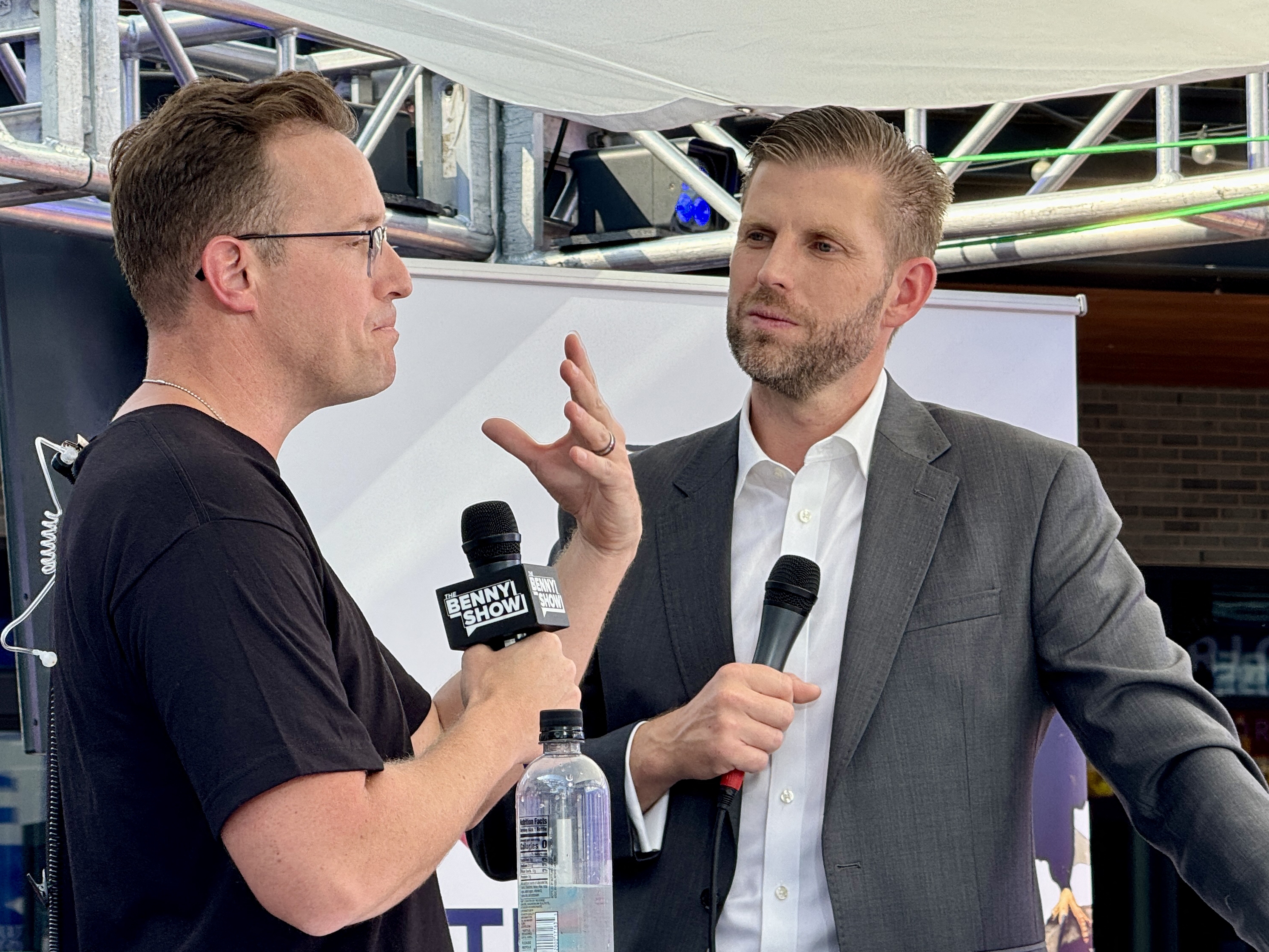 caption: Political commentator and YouTuber Benny Johnson (left) speaks with Eric Trump, a son of former President Donald Trump, during the 2024 Republican National Convention in Milwaukee. Johnson made videos for Tenet Media. The Justice Department accused a company matching Tenet's description of working closely with employees of Russian state broadcaster RT to covertly spread pro-Russian narratives in the United States. Johnson says he was not aware of Tenet's ties to Russia.