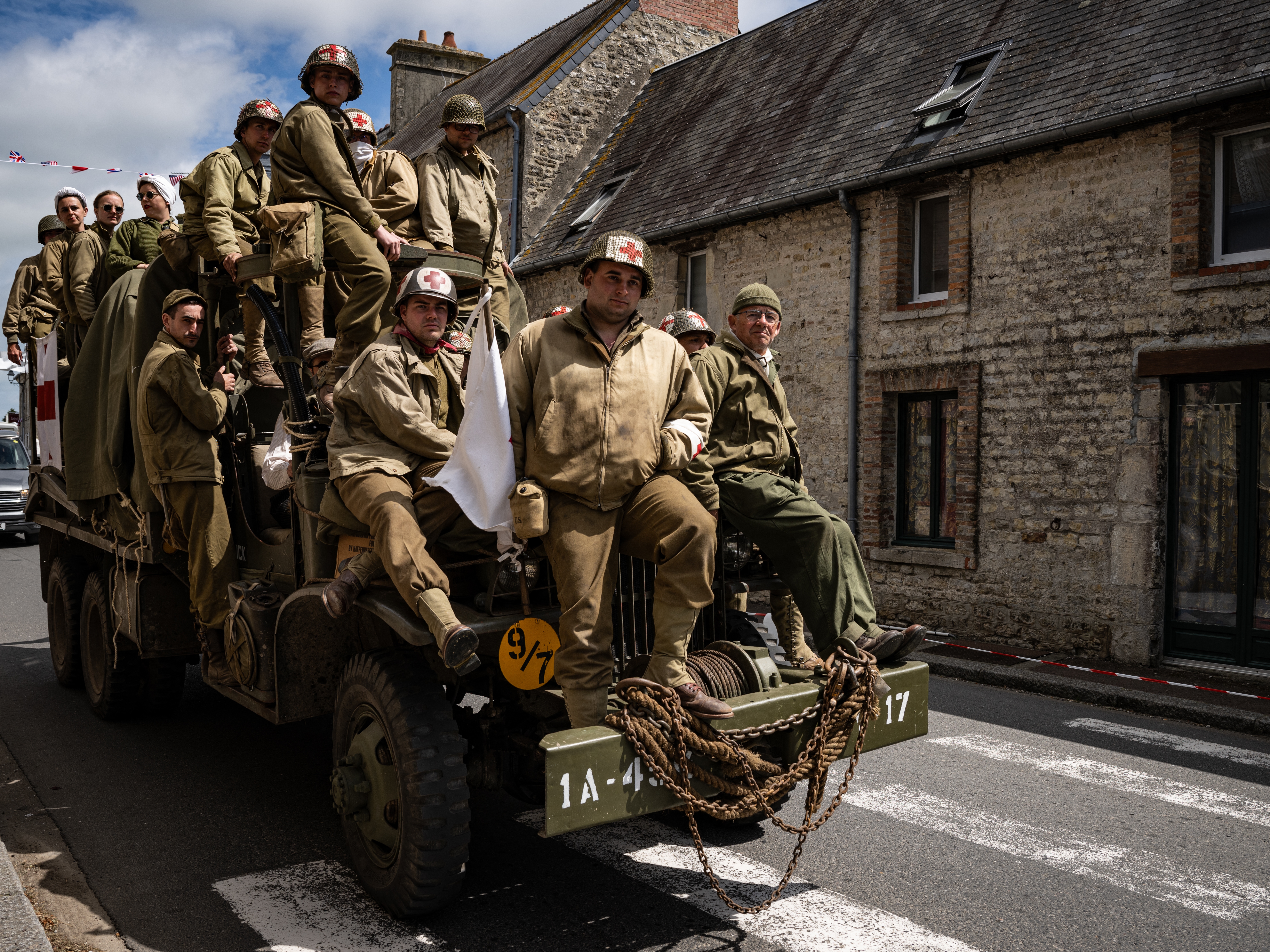 caption: Enthusiasts wearing replica World War II military attire ride atop a WWII-era military truck in Saint-Côme-du-Mont, northwestern France, on Tuesday, as part of the D-Day commemorations marking the 80th anniversary of the World War II Allied landings in Normandy. The D-Day ceremonies on June 6 this year mark the 80th anniversary.
