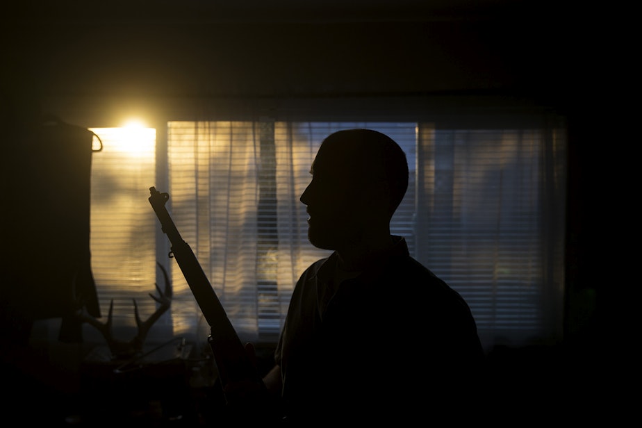 caption: Josh Young stands for a portrait while holding his M1 Garand firearm on Friday, February 21, 2020, at his home in Seattle.