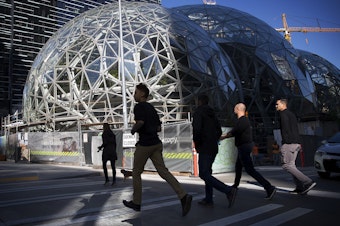 caption: A group of people jog across Lenora Street in front of Amazon's biodomes, in Seattle.