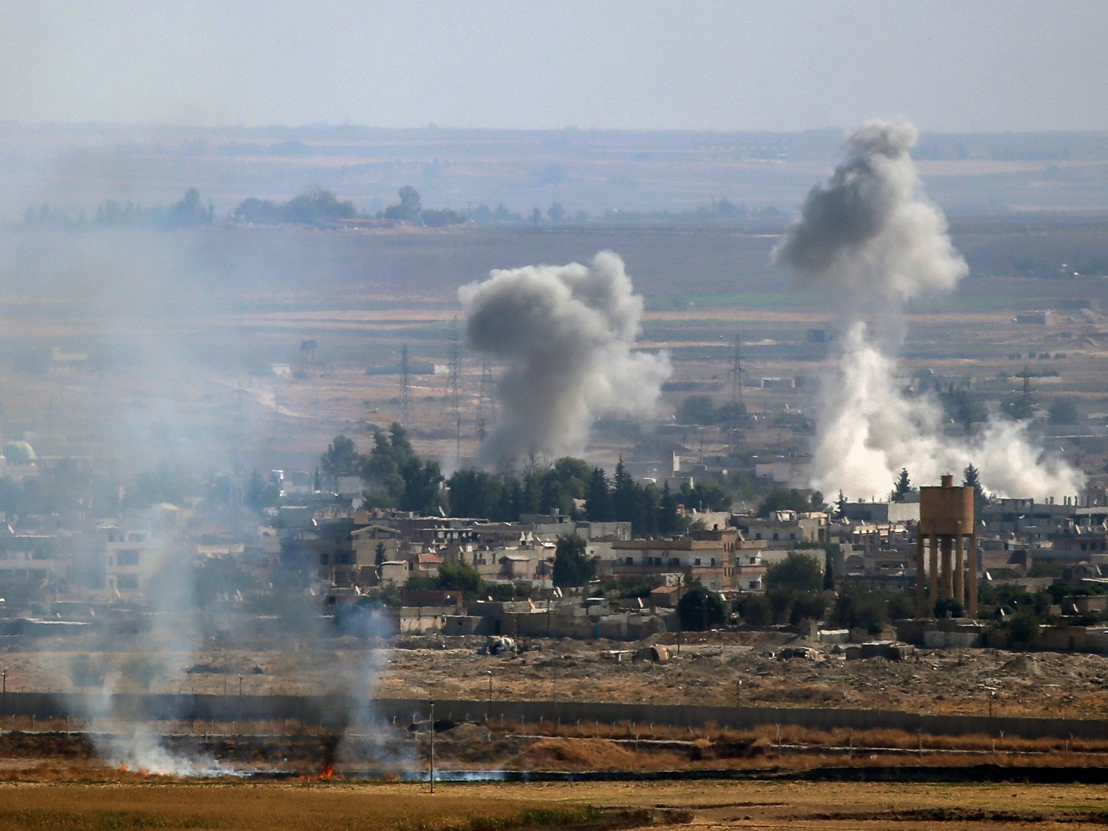 caption: A photo taken from Turkey's Sanliurfa province shows smoke rising after Turkish Armed Forces hit targets in Rasulayn, a town east of the Euphrates River in northern Syria, on Monday.
