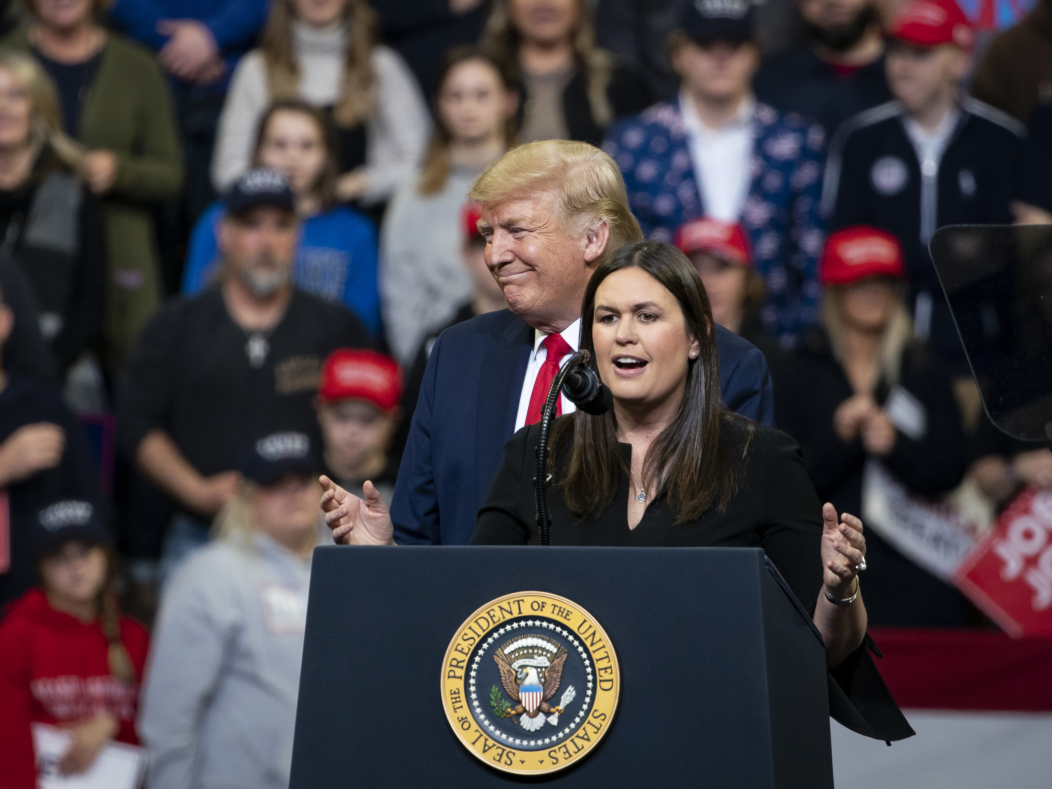 caption: Sarah Huckabee Sanders, former White House press secretary, speaks as U.S. President Donald Trump listens during a rally in Des Moines, Iowa, on Jan. 30.