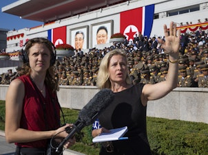caption: <em>All Things Considered</em> host Mary Louise Kelly (right) records a standup with producer Becky Sullivan at Kim Il Sung Square in Pyongyang ahead of a military parade marking the 70th anniversary of North Korea's founding.