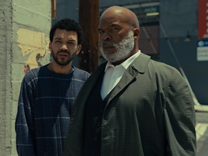 caption: Aren (Justice Smith) and Roger (David Alan Grier) in <em>The American Society of Magical Negroes.</em>
