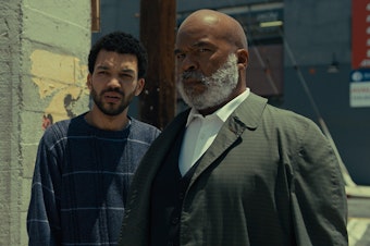 caption: Aren (Justice Smith) and Roger (David Alan Grier) in <em>The American Society of Magical Negroes.</em>